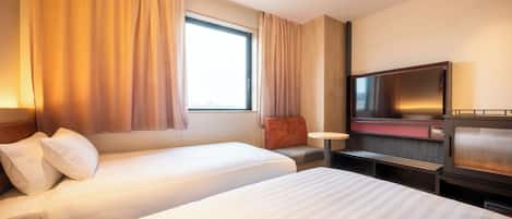 Habitación de hotel con dos camas, televisión, una mesita y ventana con cortinas.