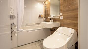 A modern bathroom with a bathtub, a separate toilet, a vanity with a mirror, and a shower area.