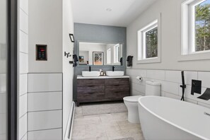 A modern bathroom with a double sink vanity, a toilet, and a freestanding bathtub. - Epic House for Groups: 10 Mins to Sunday River (Bethel)