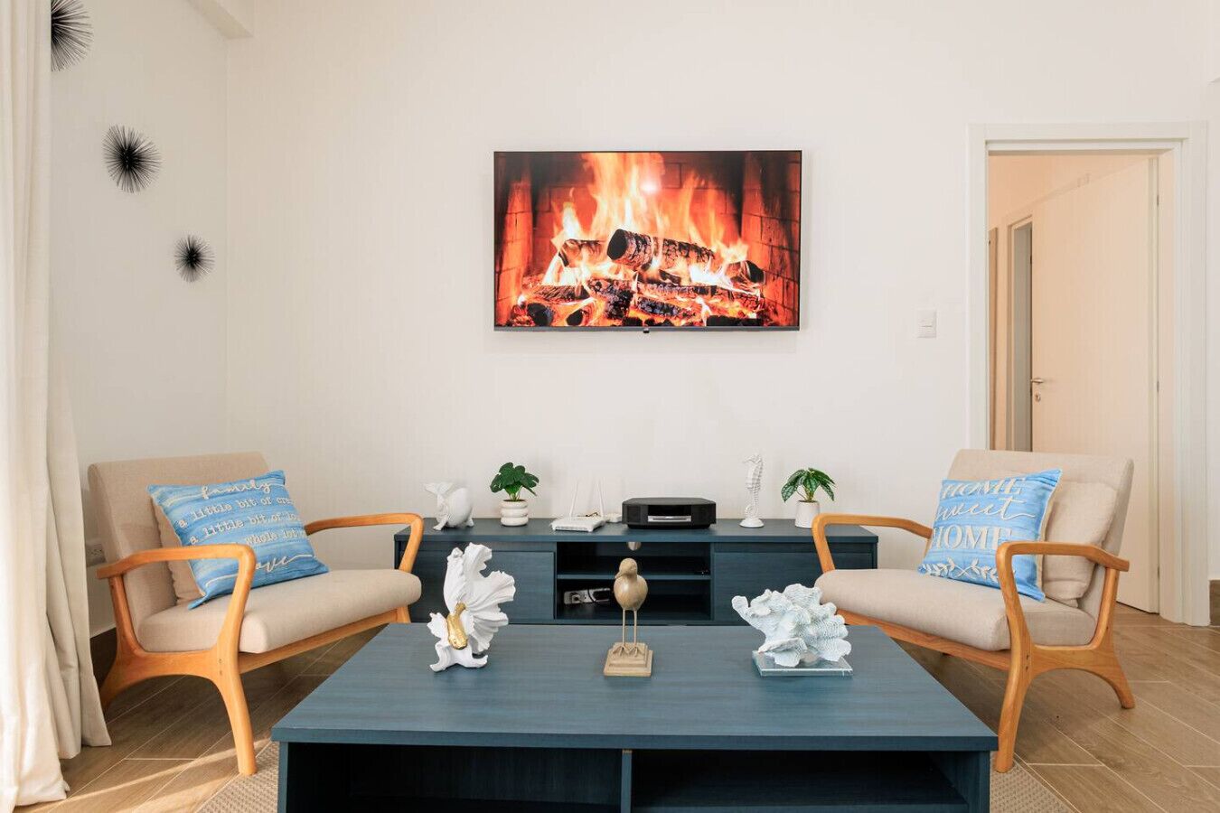 Un salón con dos sillones, una mesa de centro y una chimenea encendida.