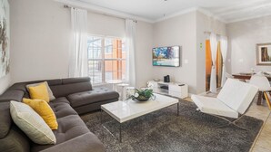 A modern living room with a sectional sofa, a white coffee table, a white armchair, and a ceiling fan. - Paradise 4Bd w Private Pool & Waterpark 2941 (Kissimmee)