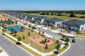 Un barrio residencial con casas modernas, un parque infantil y una cancha de baloncesto.