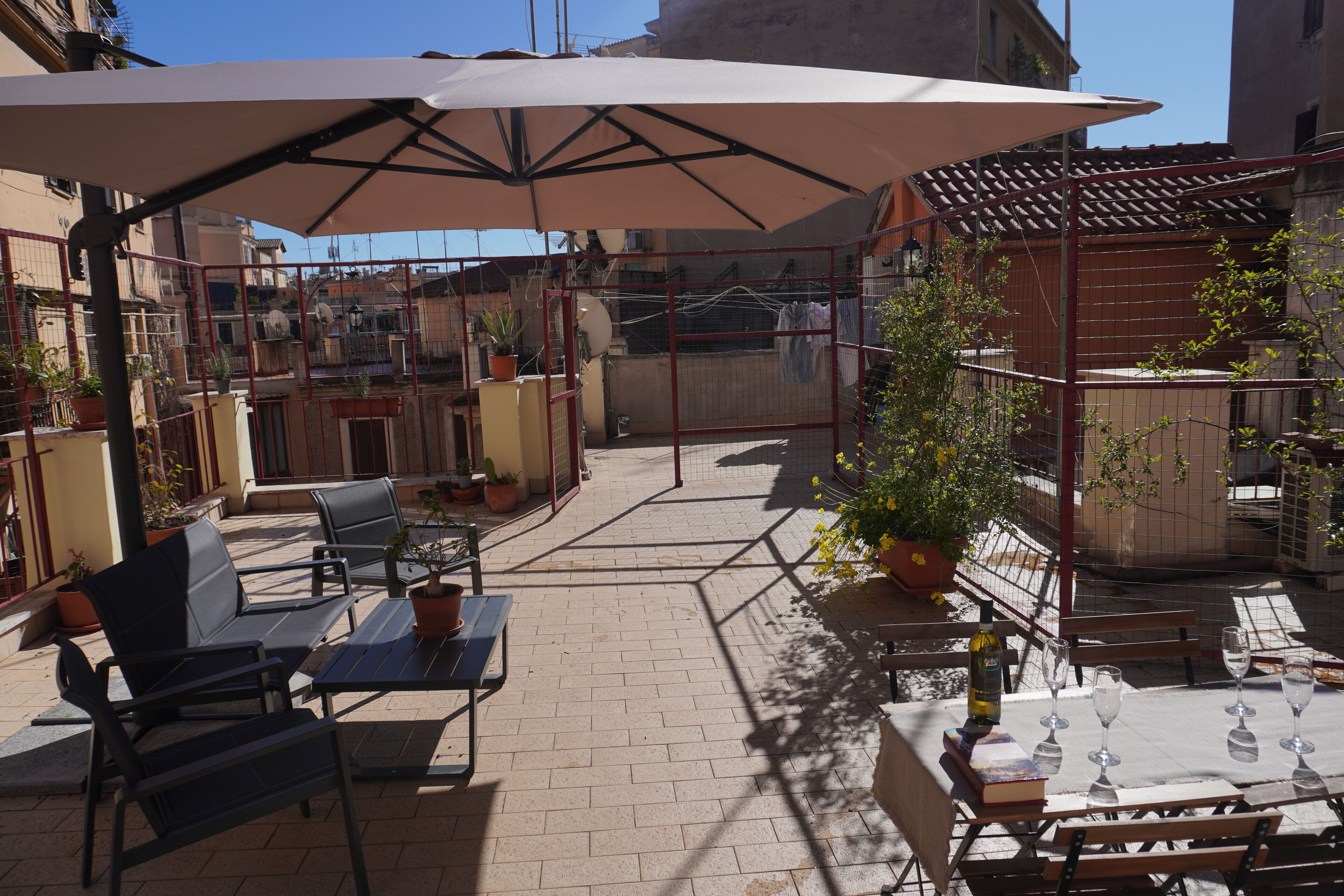 An outdoor patio area with tables and chairs, umbrellas, and potted plants.