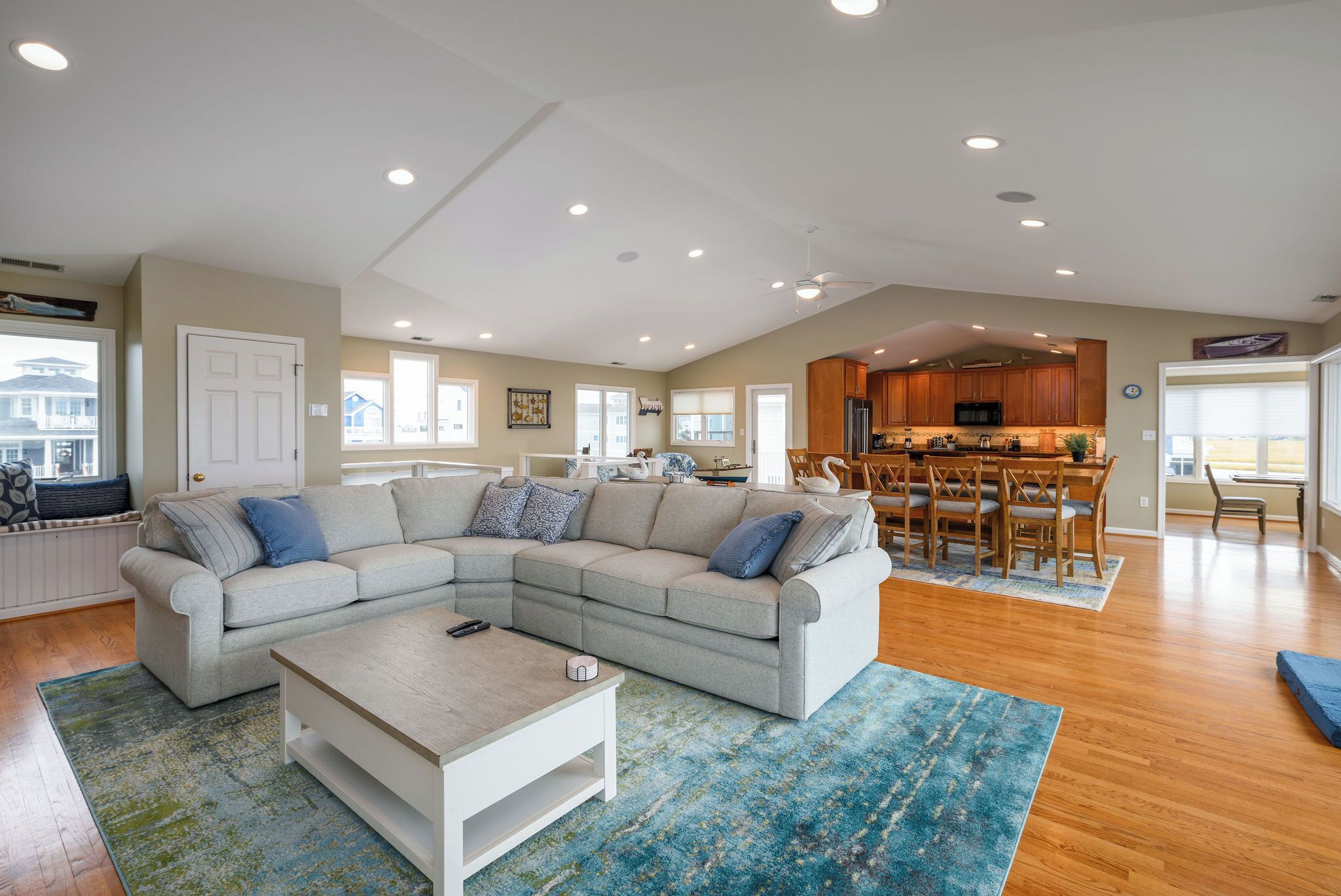 A spacious living room with a sectional sofa, a coffee table, and a dining area with a wooden table and chairs.