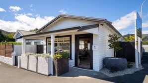 Un petit bâtiment d’un seul étage, doté d’un toit en pente, d’un porche abrité et d’un intérieur visible, comprenant un espace cuisine.