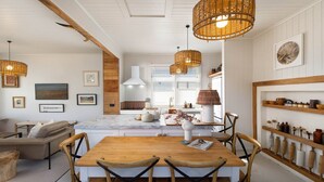 Une cuisine moderne avec un îlot en marbre, des chaises en bois et des lustres suspendus en osier.