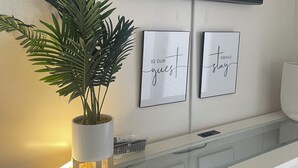 A modern room with a flat-screen TV mounted on the wall, a glass-top desk, a potted plant, and two framed motivational quotes. - Modern studio in Grand Cayman, West Bay w / private patio & short walk to beach! (West Bay)