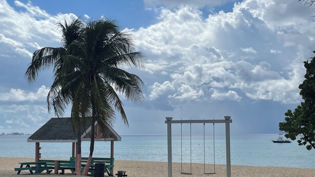 A beach with a swing set, a picnic table, and a small shelter. - Modern studio in Grand Cayman, West Bay w / private patio & short walk to beach! (West Bay)