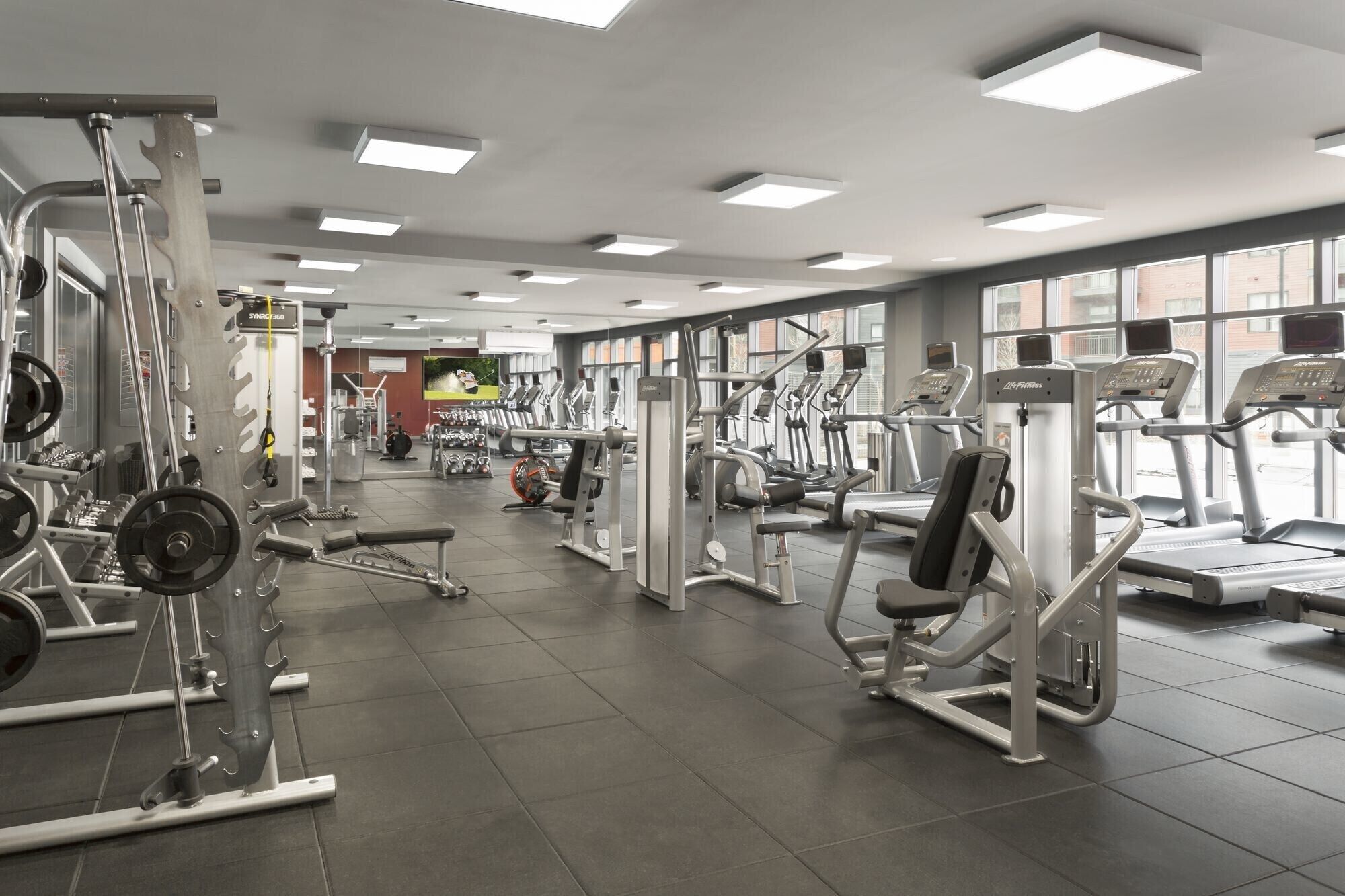 Une salle de sport équipée de divers appareils d’exercice, notamment des tapis de course, des appareils de musculation et des poids libres.
