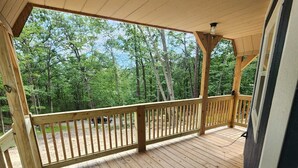 A wooden deck with a railing, surrounded by trees.