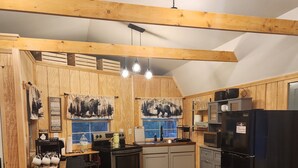 A kitchen with wooden beams, a dining table with a vase of flowers, and a refrigerator.