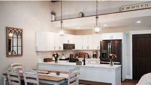 A modern kitchen with white cabinetry, a central island, and pendant lighting. - Spacious 2BR Condo - Minutes to DT Mystic (Stonington)