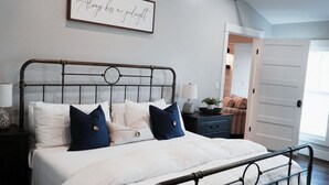 A neatly made bed with white and blue pillows, a metal headboard, and a bedside table with a lamp. - Spacious 2BR Condo - Minutes to DT Mystic (Stonington)