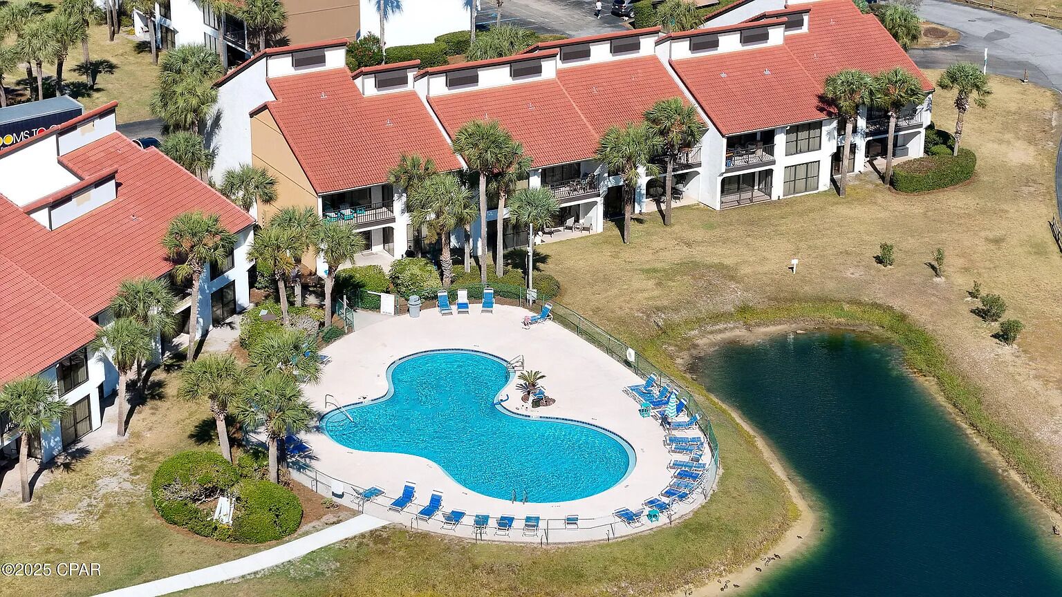 Vista aérea de un hotel con piscina, palmeras y una zona de playa.