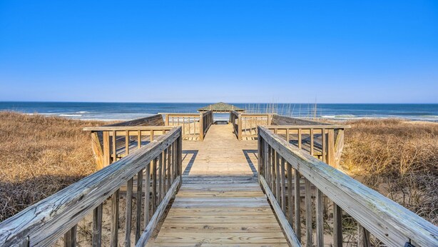 A wooden boardwalk leading to a beach with a clear blue sky. - Ocean's Outside: Relaxing Oceanfront Escape (Kill Devil Hills)