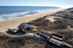 A beach with wooden walkways, a small shelter, and a sandy path leading to the ocean. - Ocean's Outside: Relaxing Oceanfront Escape (Kill Devil Hills)
