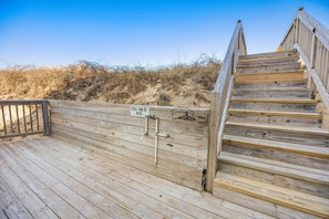 Eine Holztreppe führt zu einem Strandabschnitt, auf einem Schild steht: 'Bitte Wasser abstellen.'