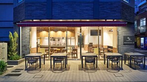A hotel with a modern exterior, a visible entrance, and outdoor seating area. - TORANOMONHOLIC HOTEL (Tokyo)
