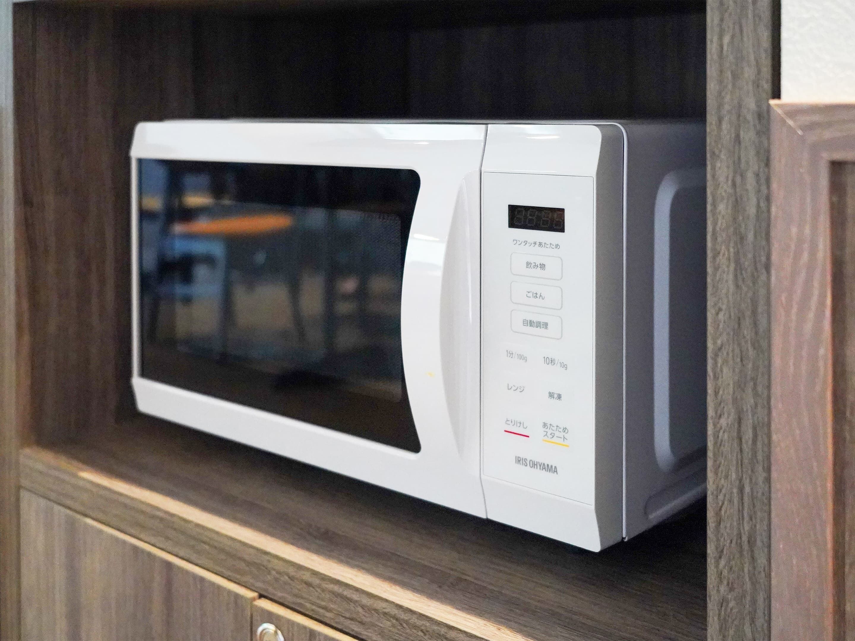 A white microwave in a wooden cabinet.