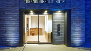 The exterior of Toranomonic Hotel with a modern brick facade and a glass entrance. - TORANOMONHOLIC HOTEL (Tokyo)