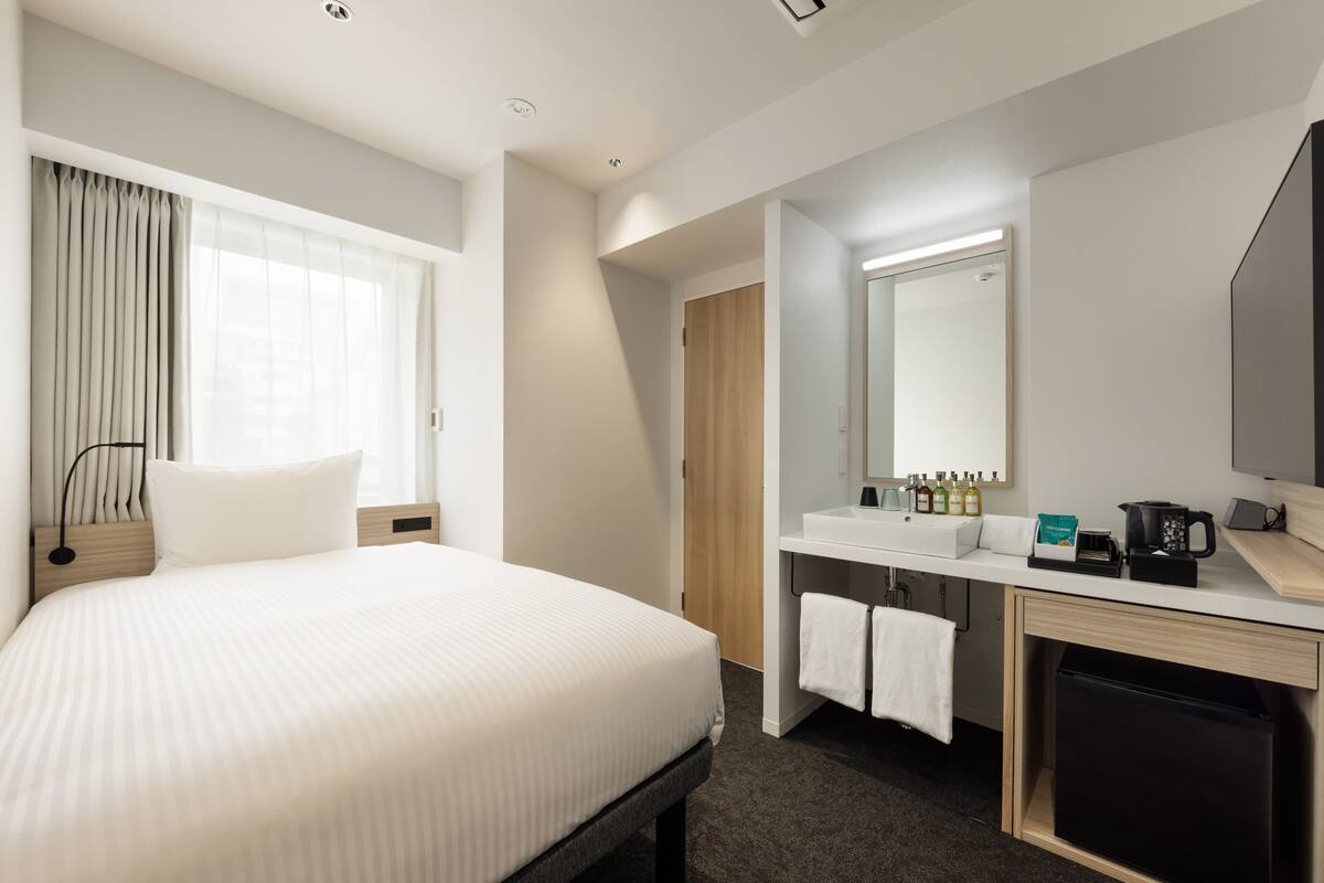 A hotel room with a large bed, a bathroom with a sink and mirror, and a television.
