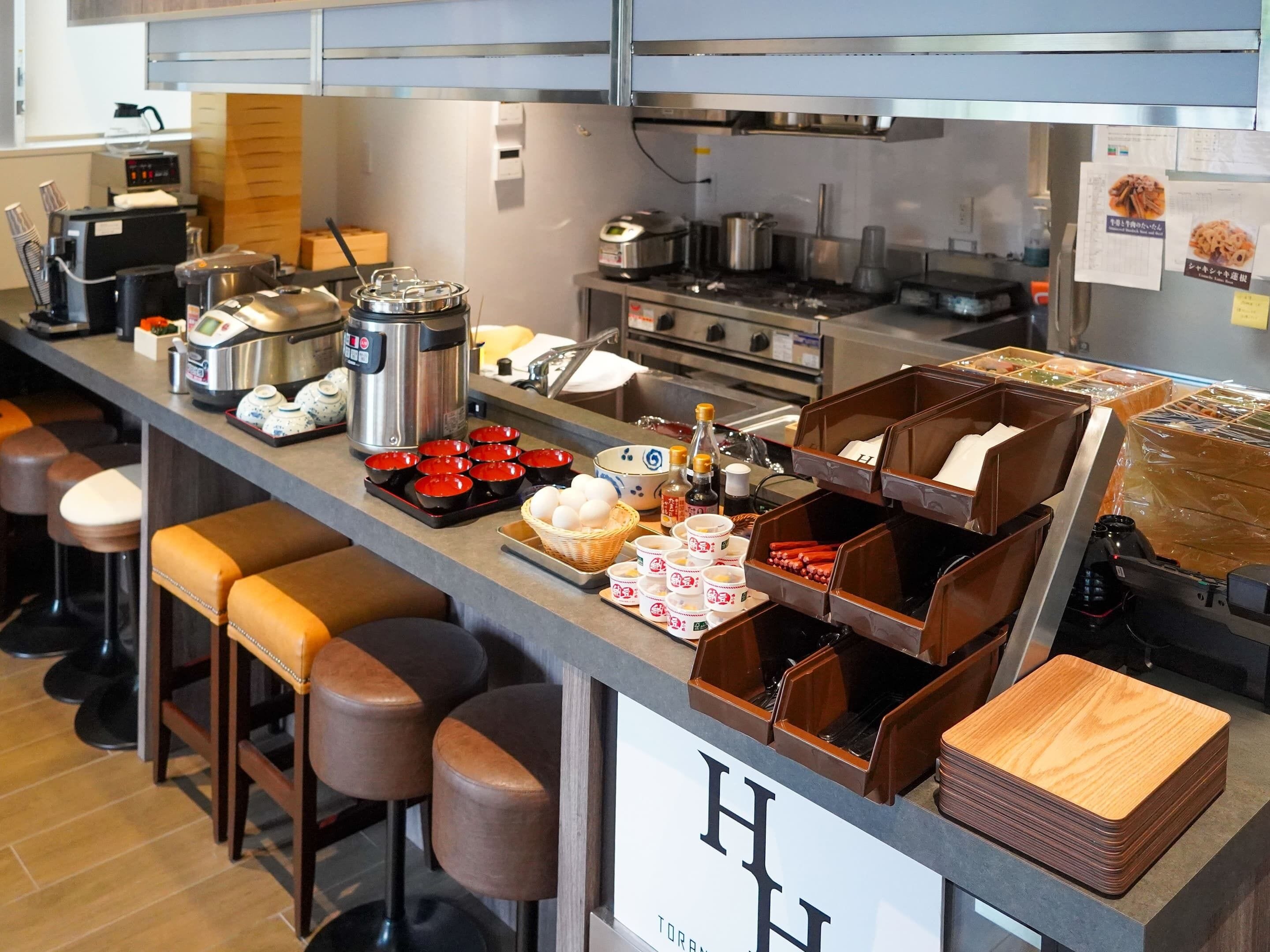 A commercial kitchen with stainless steel appliances, a coffee machine, and various food containers.