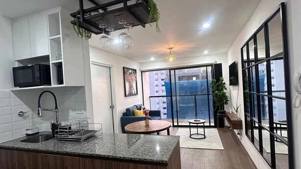 A modern kitchen with a central island, white cabinets, and a dining area with a blue sofa. - Cozy apartment with ocean view (Lima)
