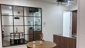 A dining area with a round table, two chairs, a vase with flowers, a large mirror, and a wooden cabinet. - Cozy apartment with ocean view (Lima)