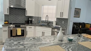 A kitchen with white cabinets, a marble countertop, a stainless steel range, and a window with blinds. - Serene 2-bedroom villa near beach in lovely Boca Raton (Boca Raton)
