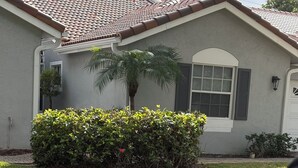 A house with a tiled roof, a window with shutters, and a well-maintained hedge. - Serene 2-bedroom villa near beach in lovely Boca Raton (Boca Raton)