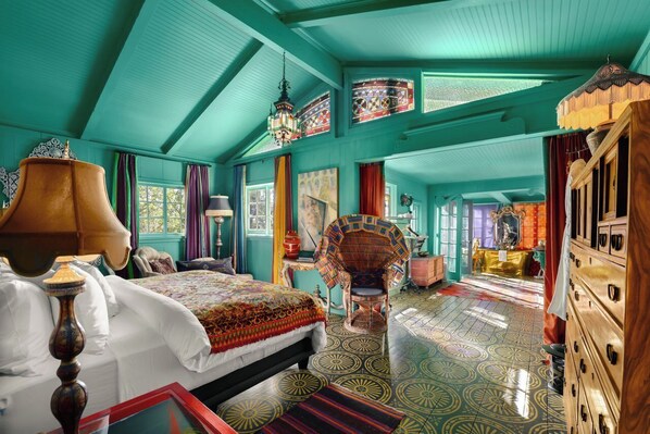 A spacious room with a large bed, a chair, and a dresser.
