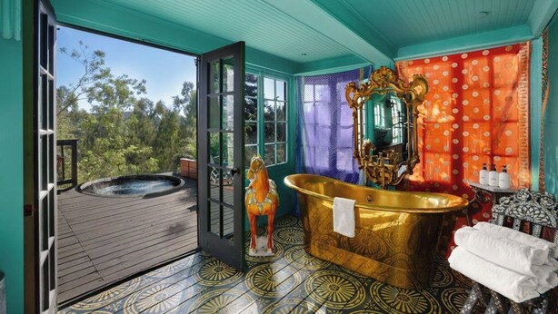 Ein Badezimmer mit einer goldenen Badewanne, einer Pferdestatue und einem großen Spiegel.