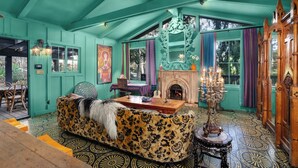 Ein Zimmer mit türkisfarbenen Wänden, einem gemusterten Boden, einem Kamin und einem großen Spiegel.