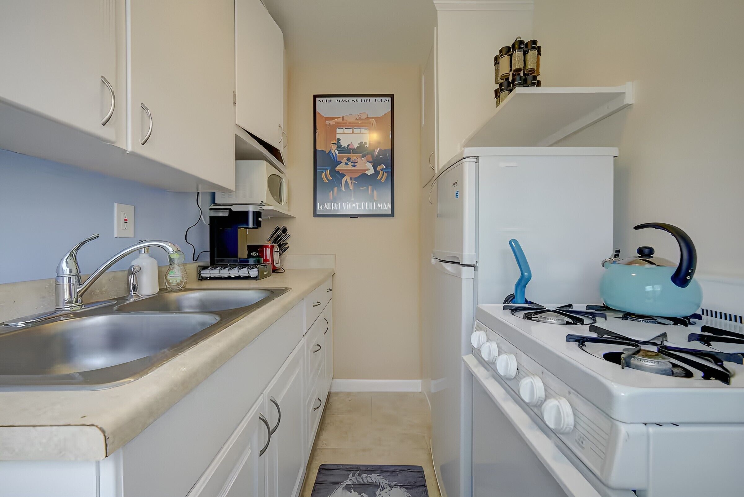 A compact kitchen with a stove, sink, and cabinets.