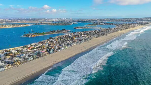 An aerial view of a coastal city with a long beachfront, clear blue waters, and a dense urban area with buildings. - Studio by the Beach • A/C, FREE Bikes & Beach Gear (San Diego)