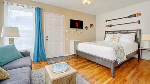 A bedroom with a bed, a TV, and two paddles on the wall. - Studio by the Beach • A/C, FREE Bikes & Beach Gear (San Diego)