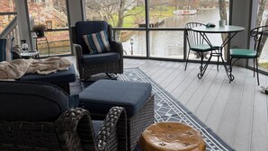 Een ruim terras met rieten meubels, een ronde tafel en stoelen.