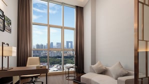 Une chambre d’hôtel moderne dotée d’une grande fenêtre, d’un bureau, d’une chaise et d’un canapé.