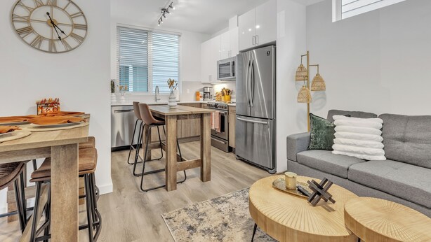Eine moderne Küche mit einem Edelstahl-Kühlschrank, einem Holztisch und Barhocker.