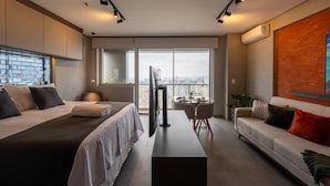 A modern hotel room with a large bed, a sofa, a dining table, and a TV. - Modern studio apartment with queen-size bed in Cityplex Osasco. (Osasco)