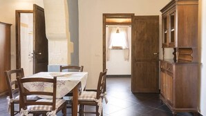 Ein Essbereich mit einem Tisch für vier Personen, Holzsesseln und einem Schrank.