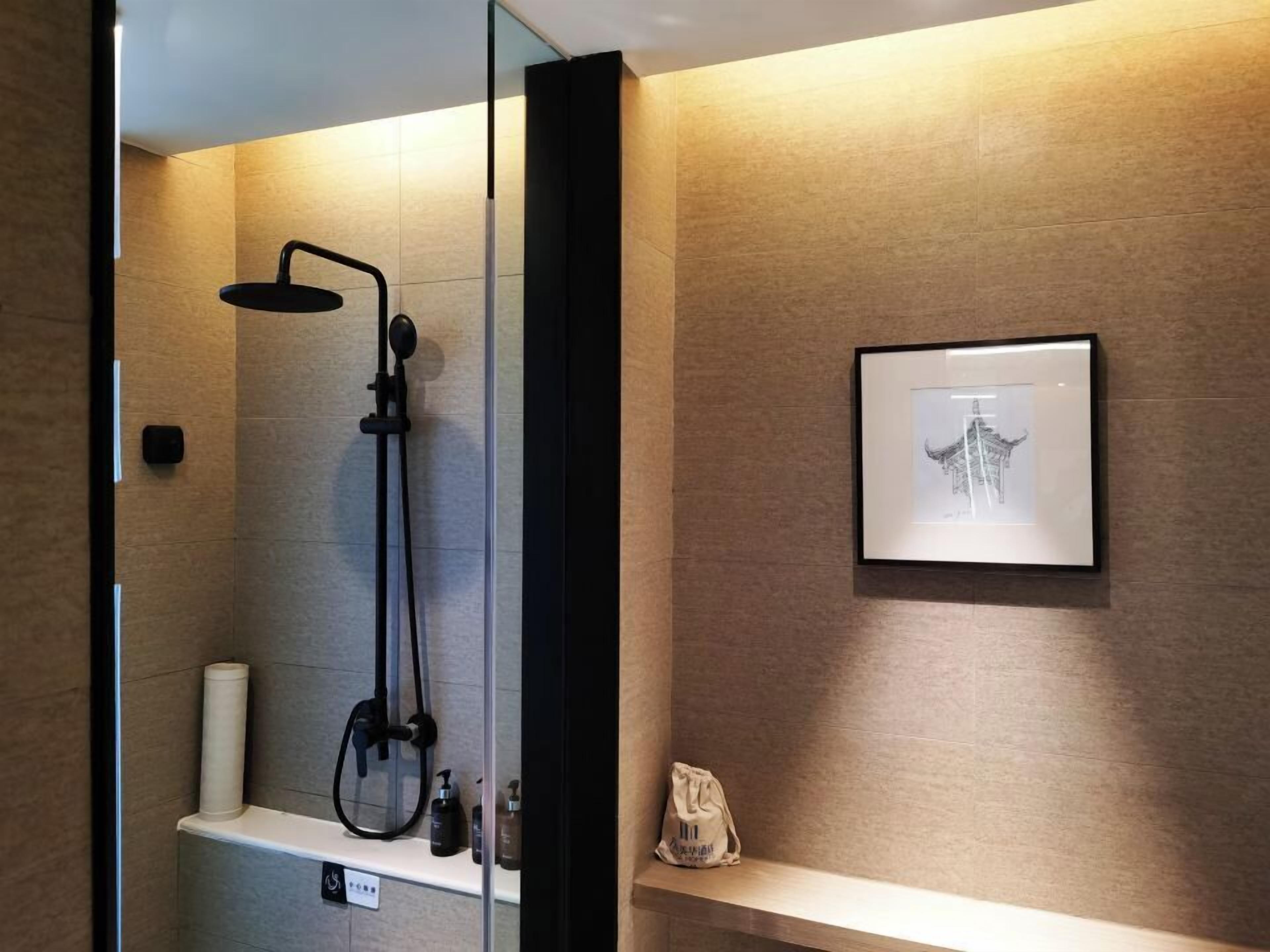 Un baño moderno con cabina de ducha de vidrio, un perchero y un cuadro en la pared.