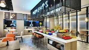 A modern restaurant interior with a central island, seating area, and a kitchen visible in the background. - Wanda Moments Heze (Heze)