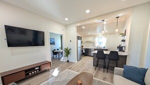 Un salon moderne avec un téléviseur à écran plat, une table basse en bois et un canapé agrémenté de coussins bleus.