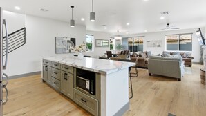 A modern kitchen with a marble island, grey cabinets, and a built-in oven. - Brand new Beautiful Build in the heart of Tempe (Tempe)