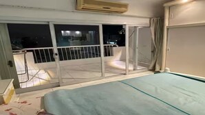 Een slaapkamer met een bed, nachtkastje, raam met uitzicht en een airconditioning.