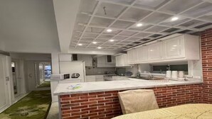 Een moderne keuken met witte kasten, een accentmuur van baksteen en een centraal eiland.