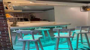 Een moderne bar met witte barkrukken en een glazen scheidingswand.