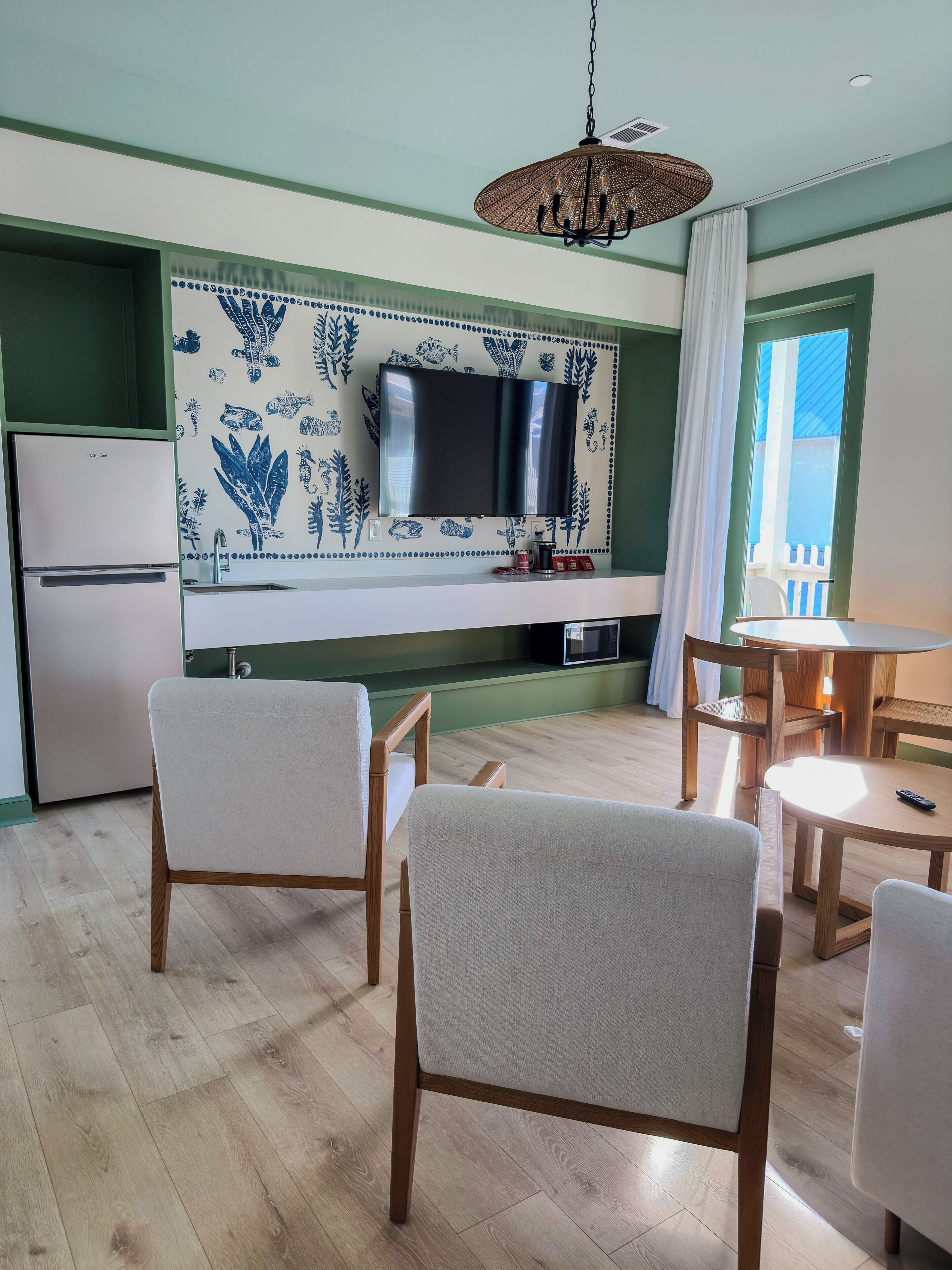 Una cocina moderna con un televisor de pantalla plana, sillas de madera y una mesa de comedor.