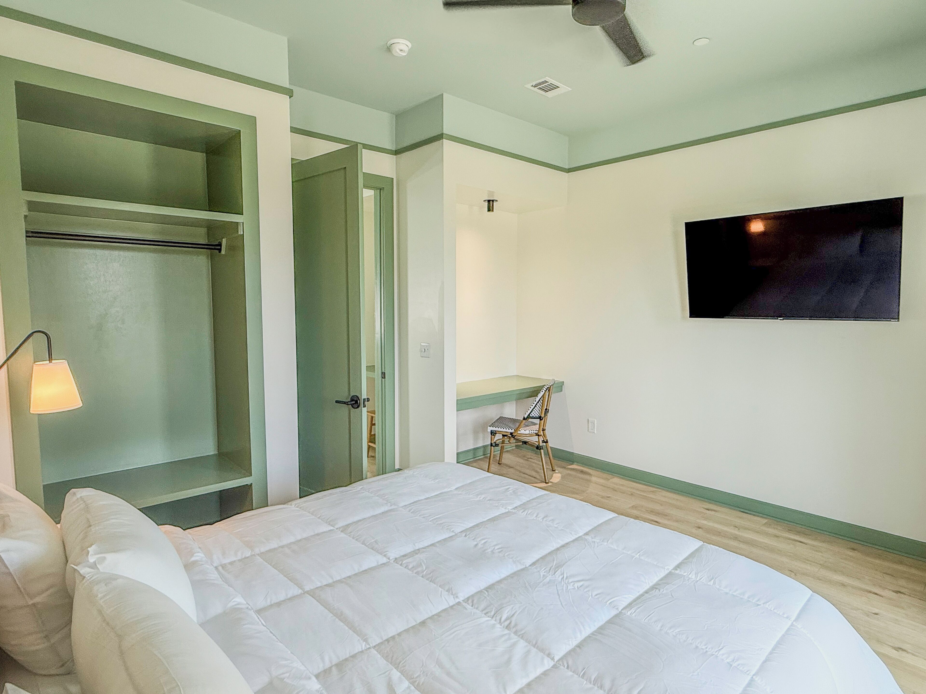 Un dormitorio con cama, televisor, silla y armario.